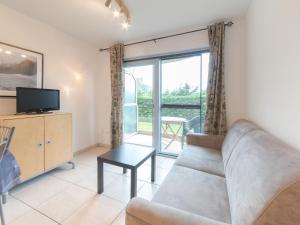 a living room with a couch and a tv at Studio Deauville II 010 with parking by Interhome in Bredene +8 photos