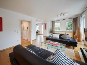 a living room with a black couch and a glass table at Holiday Home Am Golf- und Reitpark by Interhome in Niederhelden
