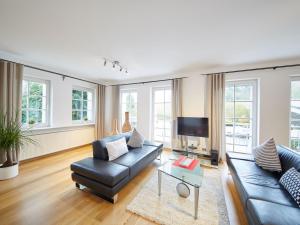 a living room with a black leather couch and a tv at Holiday Home Am Golf- und Reitpark by Interhome in Niederhelden