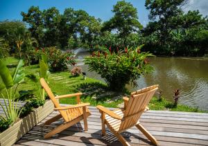 2 chaises assises sur une terrasse en bois à côté d'un étang dans l'établissement Hotel La Finca Buritaca by DOT Premium, à Buritaca