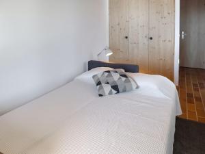 a white bed with a black and white pillow on it at Studio Les Arsets 56-2 by Interhome in Taveyannaz