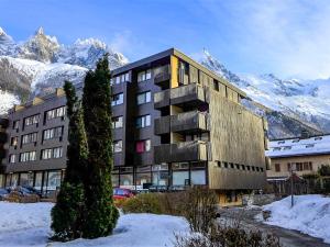 un edificio nella neve con montagne sullo sfondo di Apartment Le Mummery-10 by Interhome a Chamonix-Mont-Blanc