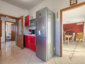 a kitchen with a stainless steel refrigerator and red cabinets at Apartment Laura by Interhome in Galižana