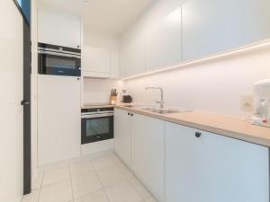 a white kitchen with white cabinets and a sink at Apartment Seaview 4 by Interhome in Bredene
