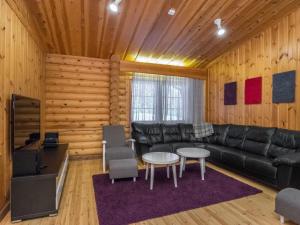 ein Wohnzimmer mit einer schwarzen Ledercouch und einem Tisch in der Unterkunft Holiday Home Karhunpesä b by Interhome in Kotila