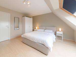 sypialnia z dużym białym łóżkiem na poddaszu w obiekcie Apartment Paul's parklane by Interhome w mieście Bredene
