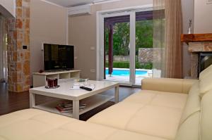 a living room with a couch and a tv and a table at Luxury Villa Bernarda in Malinska