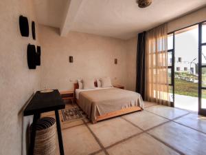 a bedroom with a bed and a large window at Tassourt Lodge in Essaouira