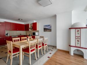 - une cuisine avec des placards rouges, une table et des chaises en bois dans l'établissement Apartment Appartement 2 by Interhome, à Schladming