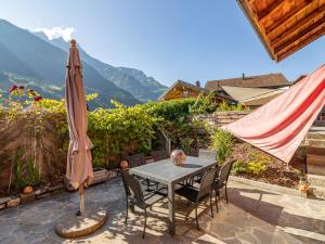 a table and chairs and an umbrella on a patio at Apartment Chalet le Riad des Neiges a- Sauna by Interhome in Val-d'Illiez