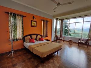 a bedroom with orange walls and a bed with red pillows at Vaga Hills Resort in Vagamon