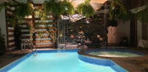a swimming pool with a hot tub next to a stone wall at Batey Hotel Boutique in Boca Chica
