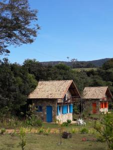 two houses with colorful doors in a field at Repouso Sol in São Thomé das Letras
