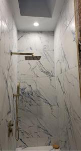 a bathroom with white marble walls and a shower at Harlem Brownstone in New York