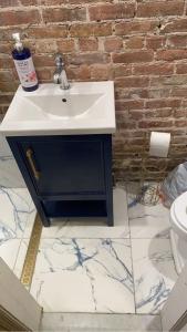 een badkamer met een wastafel en een bakstenen muur bij Harlem Brownstone in New York