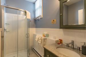 a bathroom with a glass shower and a sink at Homestead Inn in New Milford