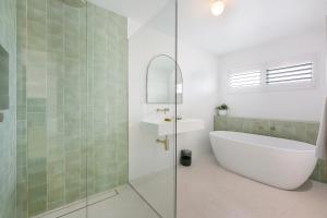 un baño con bañera y ducha de cristal en Spacious 4-Bed Villa with Mediterranean Charm, en Gold Coast 12 fotos más