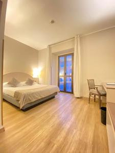 a bedroom with a bed and a desk and a window at Mokinba Hotels Baviera in Milan