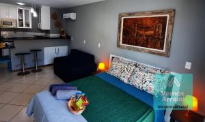 a living room with a bed and a kitchen at Loft Prainha Arraial in Arraial do Cabo