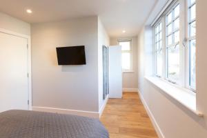 a bedroom with a bed and a tv on the wall at Hampden Apartments - The Anne in Windsor