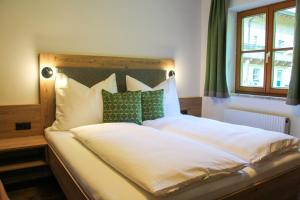 una camera da letto con un grande letto bianco con cuscini verdi di Bio Bauernhof Vorderoberlehen a Werfenweng