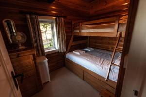 a bedroom with two bunk beds and a window at Country log cabin By Seren Property in Trawsfynydd