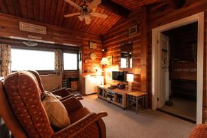 sala de estar con paredes de madera y ventilador de techo. en Country log cabin By Seren Property en Trawsfynydd