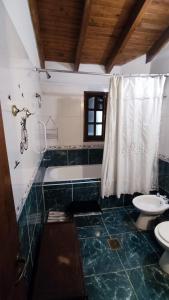 a bathroom with two toilets and a tub and a sink at Posada del Carruaje in Santa Rosa de Calamuchita