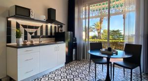 a kitchen with a sink and a table and a window at Sunrise Estudio Zebra, con vistas jardín y mar in Miami Platja