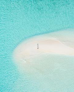 una persona in piedi su una piccola isola nell'oceano di Beach Stone a Gulhi