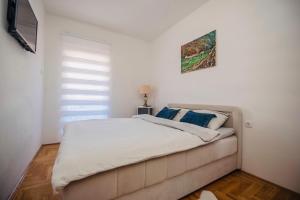 una camera bianca con un grande letto con cuscini blu di Harmonija 3 a Trebinje