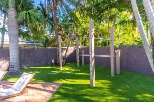 a yard with a white chair and palm trees at NEWLY RENOVATED POOL, HOT TUB, & EPIC BACKYARD in Fort Lauderdale