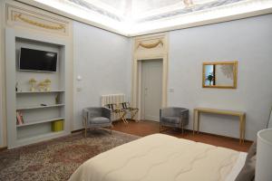 1 dormitorio con 1 cama, 2 sillas y TV en Campana Suites, en Bibbiena