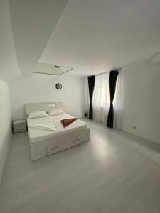 um quarto branco com uma cama e uma janela em Ramhouse em Piteşti