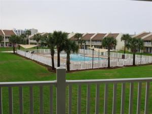 a white fence with palm trees and a swimming pool at Our Happy Place in Destin