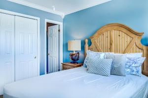 ein Schlafzimmer mit einem weißen Bett mit blauen Wänden in der Unterkunft 4 A, Three Bedroom Townhome in Destin