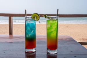 two cocktails sitting on a table near the beach at Jardim a Mar in Agonda +37 photos