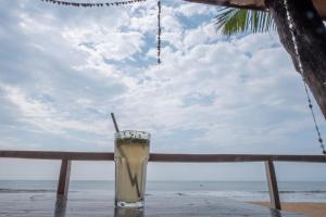 a drink sitting on a table near the beach at Jardim a Mar in Agonda