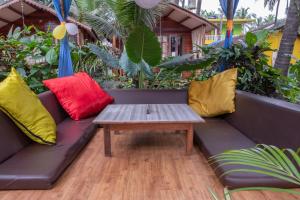 a couch with colorful pillows and a coffee table at Jardim a Mar in Agonda