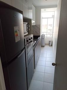 a kitchen with a black refrigerator and a white tile floor at Departamento Nuevo en Condominio Viña del Mar in Viña del Mar