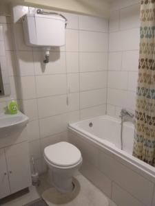 a white bathroom with a toilet and a bath tub at D6 apartment in Szeged