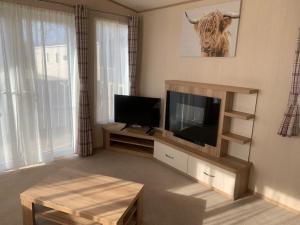 a living room with a flat screen tv and a table at Woodpecker lodge, Camelot Holiday Park, CA6 5SZ in Carlisle