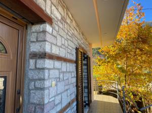 a stone building with a door and a tree at Lithotomia Mouzaki in Mouzaki