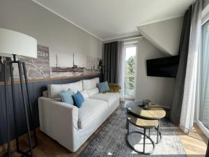 un soggiorno con divano bianco e cuscini blu di 4Hafenzeiten - Ferienwohnung NIE 9 Lotte a Niendorf