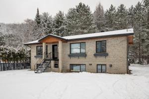 a brick house in the snow with trees at Complexe LIVTremblant by Gestion ELITE - LIV3 in Mont-Tremblant