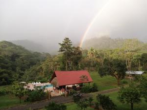 un arco iris sobre una pequeña casa con piscina en Hacienda Mil Bellezas en Quepos