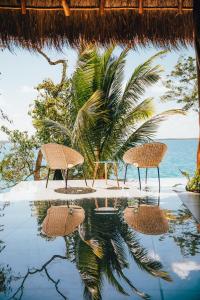 a beach scene with umbrellas and palm trees at Mia Bacalar Luxury Resort & Spa in Bacalar