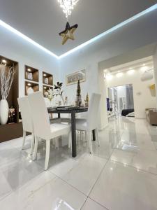 a dining room with a table and white chairs at Sea Elegance in Oliveri