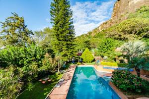 a swimming pool in a garden with a mountain in the background at Casa Jacobina Tepoztlán in Tepoztlán