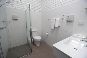 a white toilet sitting next to a white sink in a bathroom at The Town House Motor Inn in Goondiwindi